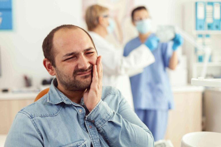 Patient holding jaw in dental pain.